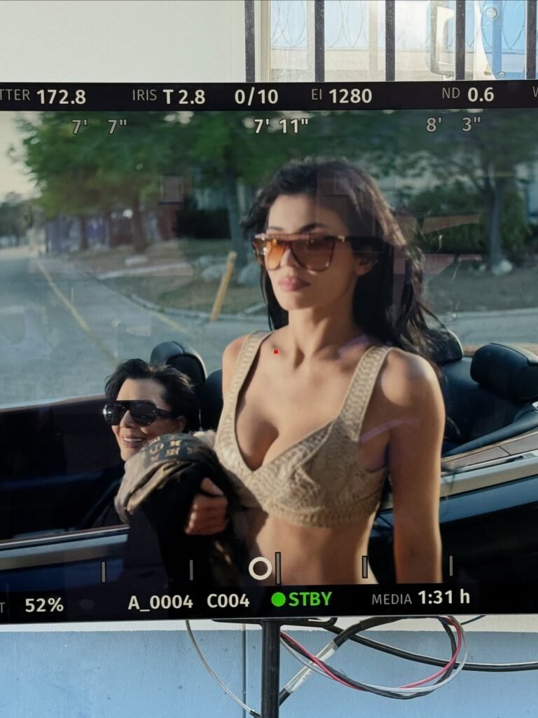 Camera viewfinder showing Kylie Jenner in convertible wearing beige outfit and sunglasses during video shoot