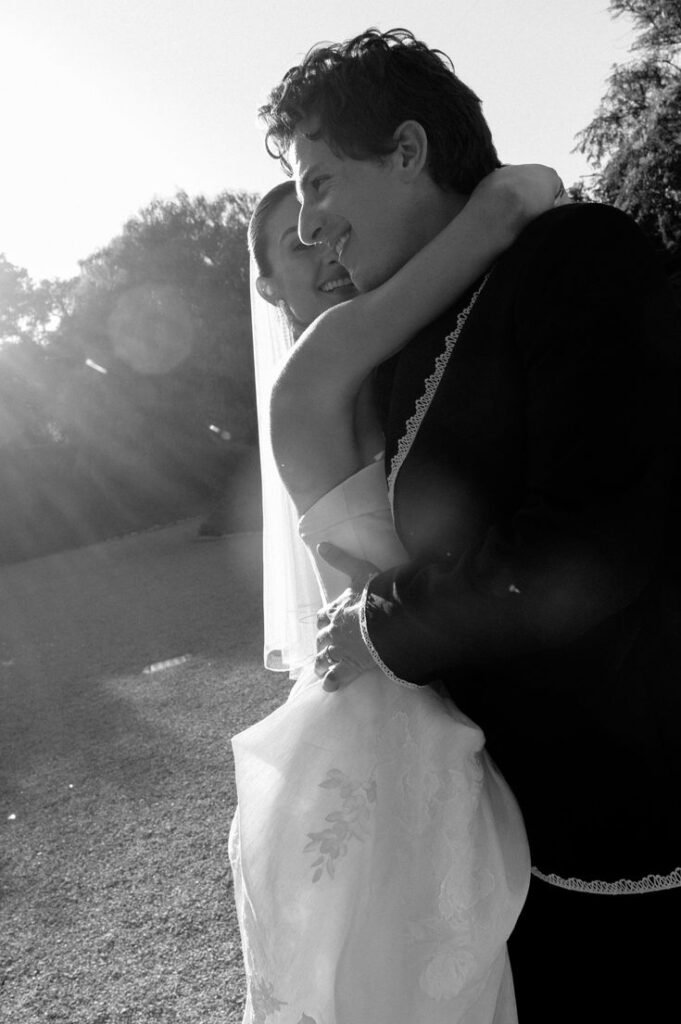 Charlie Puth embraces bride Brooke Sansone in romantic black and white wedding portrait with sunlight
