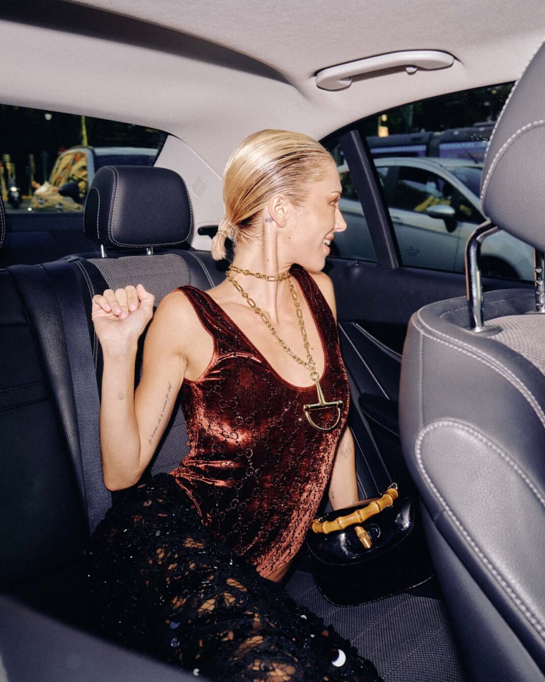 Delilah Belle in car wearing burgundy sequined top with gold chain necklace and black lace skirt arriving at Gucci presentation