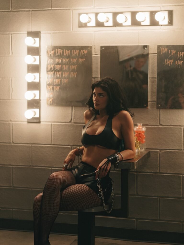 Kylie Jenner in black leather outfit sitting in dressing room with vanity mirror and Lip Kit branding