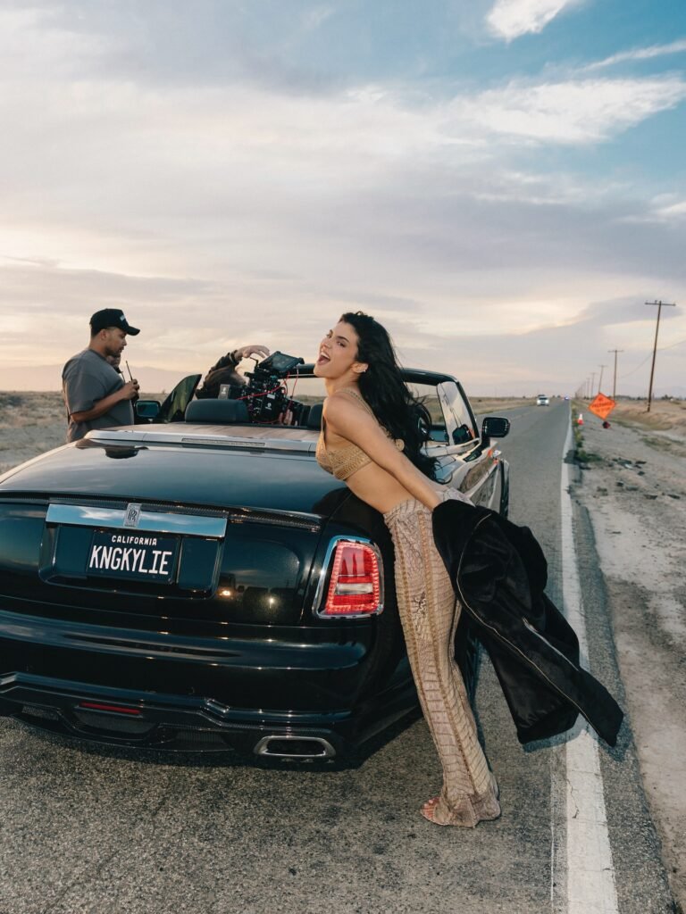 Kylie Jenner posing beside custom Rolls-Royce with KNGKYLIE vanity plate during Fourth Strike music video production