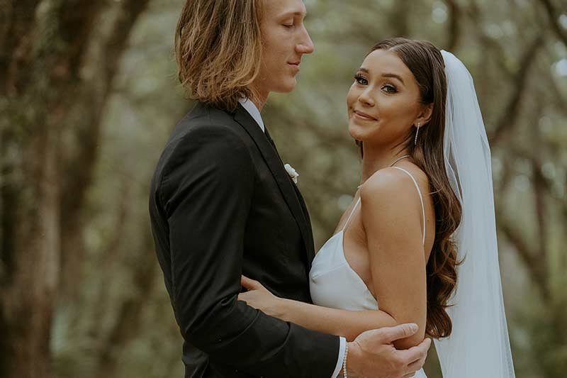 Trevor and Marissa Lawrence wedding portrait in wooded setting, bride in white gown with veil and groom in black tuxedo