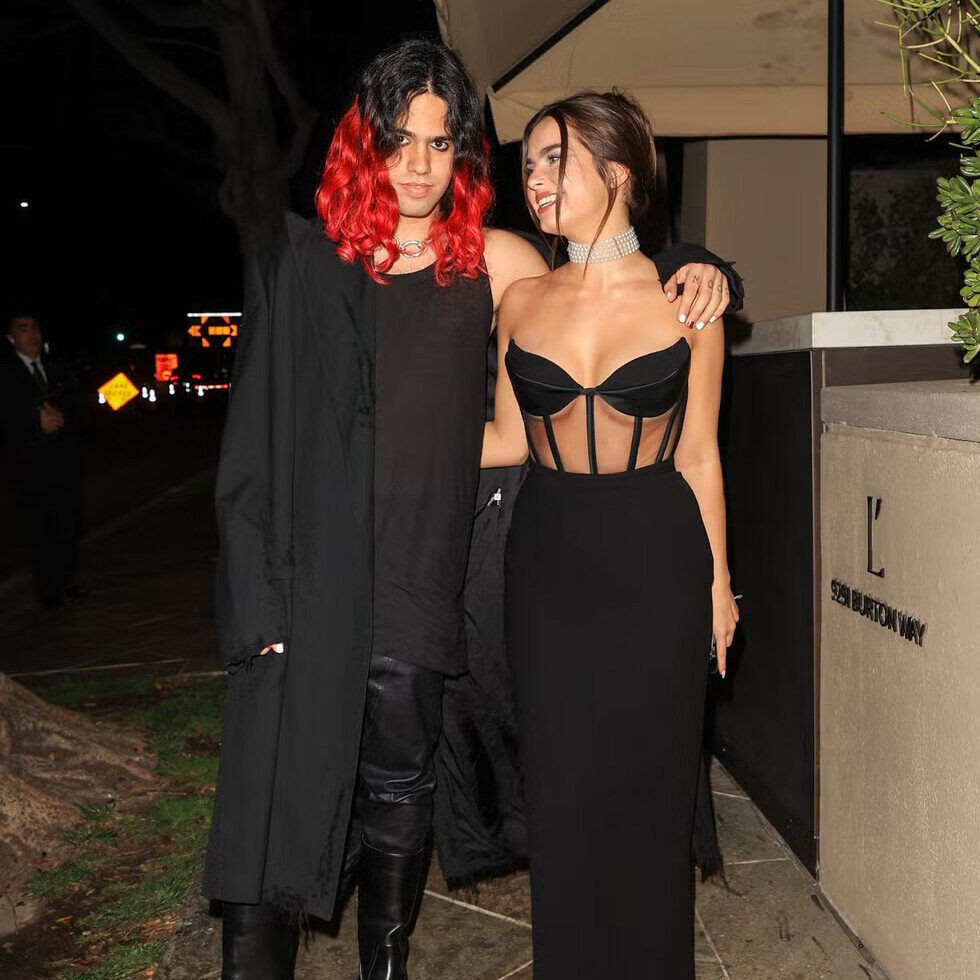 Addison Rae and Omer Fedi attending an evening event, with Rae in a black structured corset top and wide-leg pants, and Fedi in all-black attire with red-dyed hair
