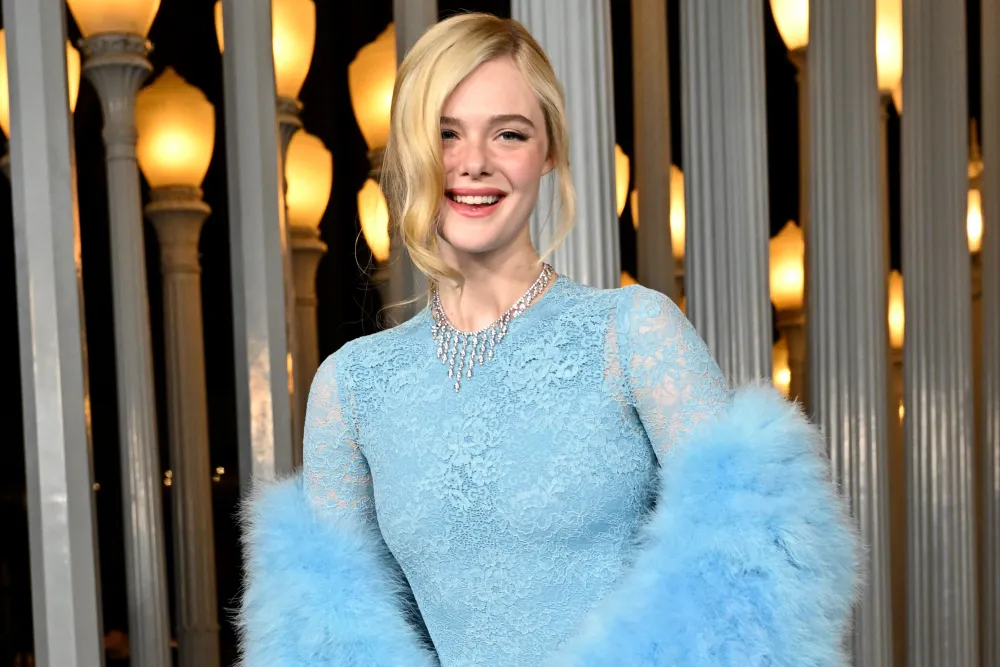 Elle Fanning smiling in baby blue Gucci lace gown with feathered sleeves and diamond necklace at 2025 LACMA Gala