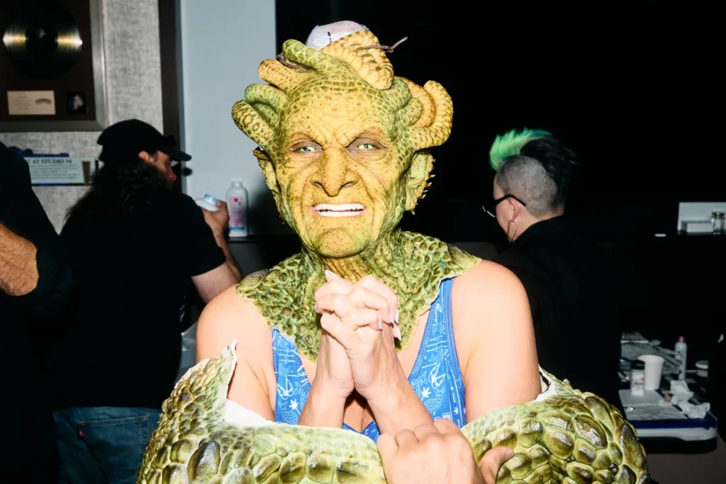 Heidi Klum in partial Medusa makeup with mechanical snake headpiece during mid-transformation stage.