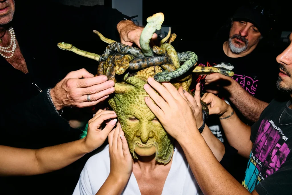 Multiple hands positioning mechanical snakes on Heidi Klum's Medusa headpiece during costume assembly