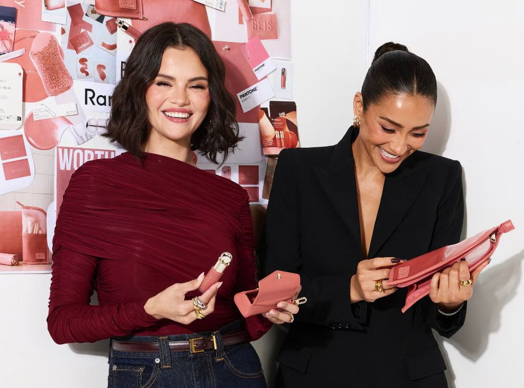 Selena Gomez and Shay Mitchell at BÉIS x Rare Beauty collaboration launch event holding rose colored travel accessories