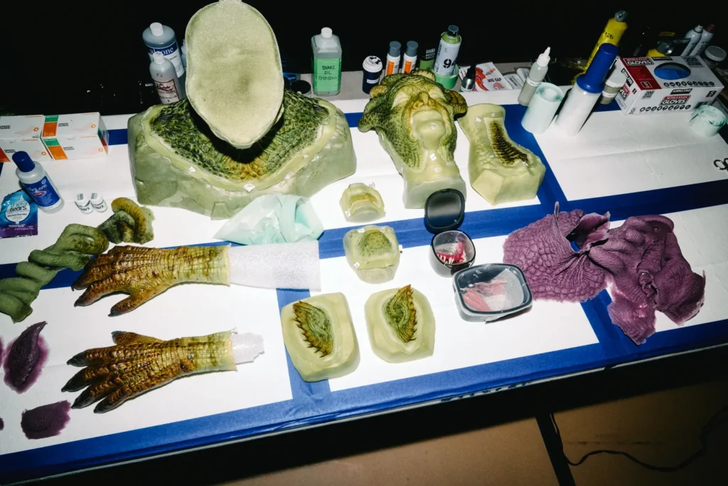 Work table displaying prosthetic body parts, mechanical snakes, and makeup supplies for Heidi Klum's Medusa costume