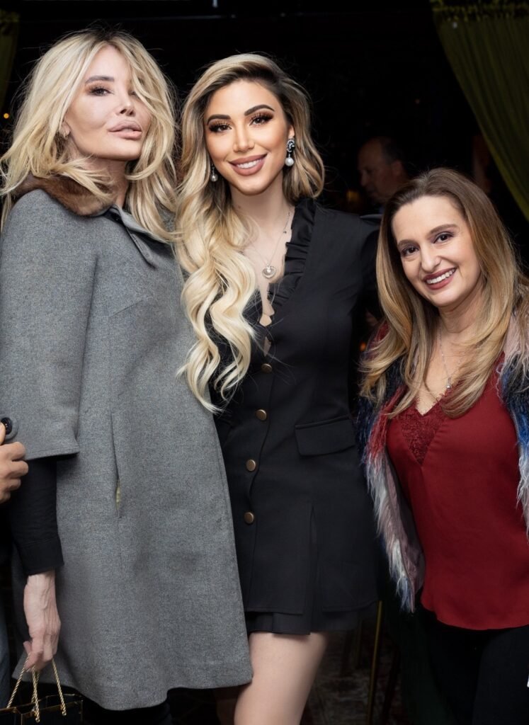 Lika O with two women at event, flanked by blonde woman in grey coat and Christine Peters in burgundy top