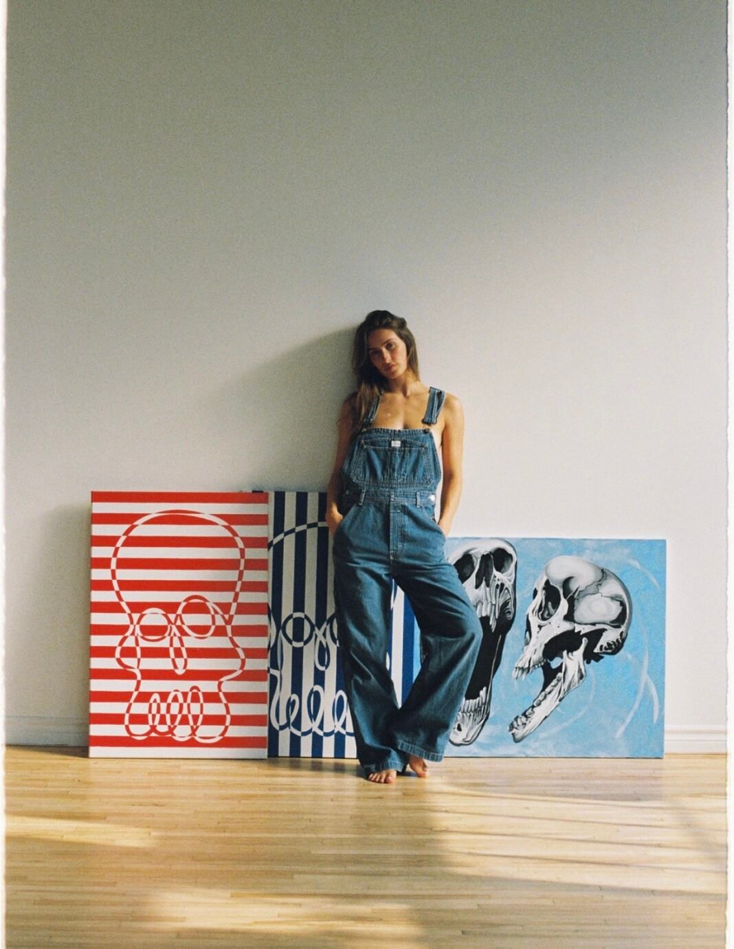 Artist with skull paintings in studio.