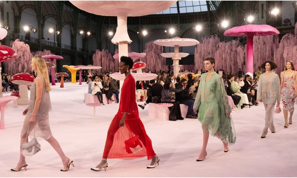 Matthieu Blazy's debut Chanel haute couture collection showcased at Paris Grand Palais with models walking runway under pink floral installation before seated audience