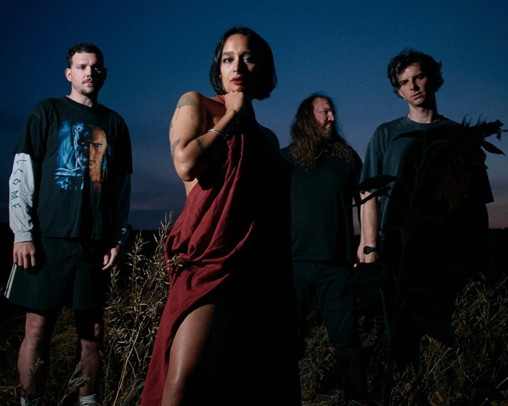 Mandy Indiana band portrait featuring Valentine Caulfield in burgundy gown with four band members photographed outdoors at twilight against deep blue sky