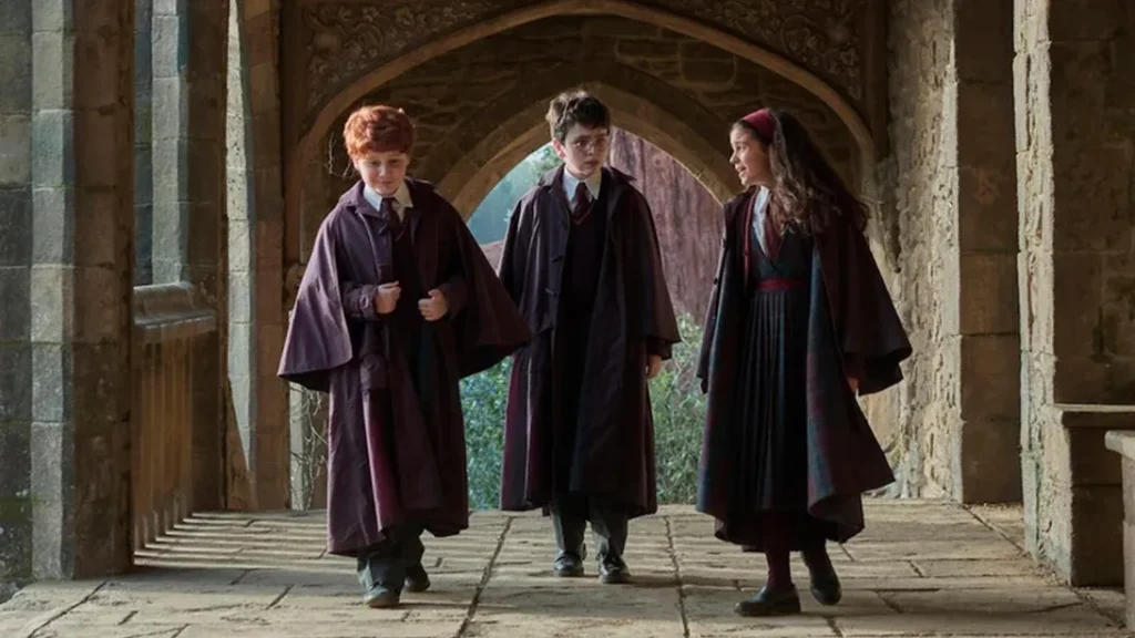 Alastair-Stout-as-Ron-Weasley-Dominic-McLaughlin-as-Harry-Potter-and-Arabella-Stanton-as-Hermione-Granger-walking-through-a-stone-archway-corridor-at-Hogwarts-in-HBOs-Harry-Potter-series-2026