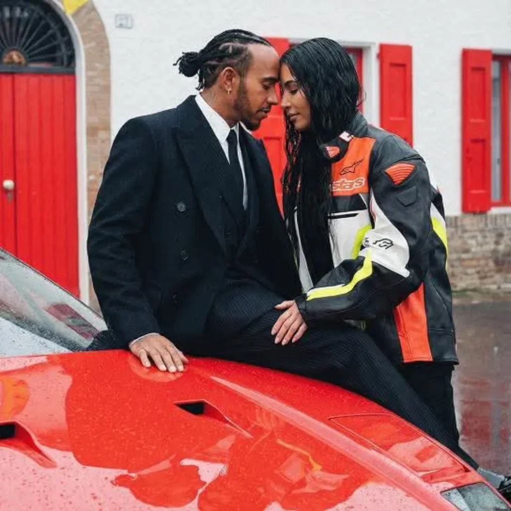 Lewis Hamilton and Kim Kardashian in an intimate moment, foreheads nearly touching, as she sits on the hood of a rain-soaked red Ferrari F40.