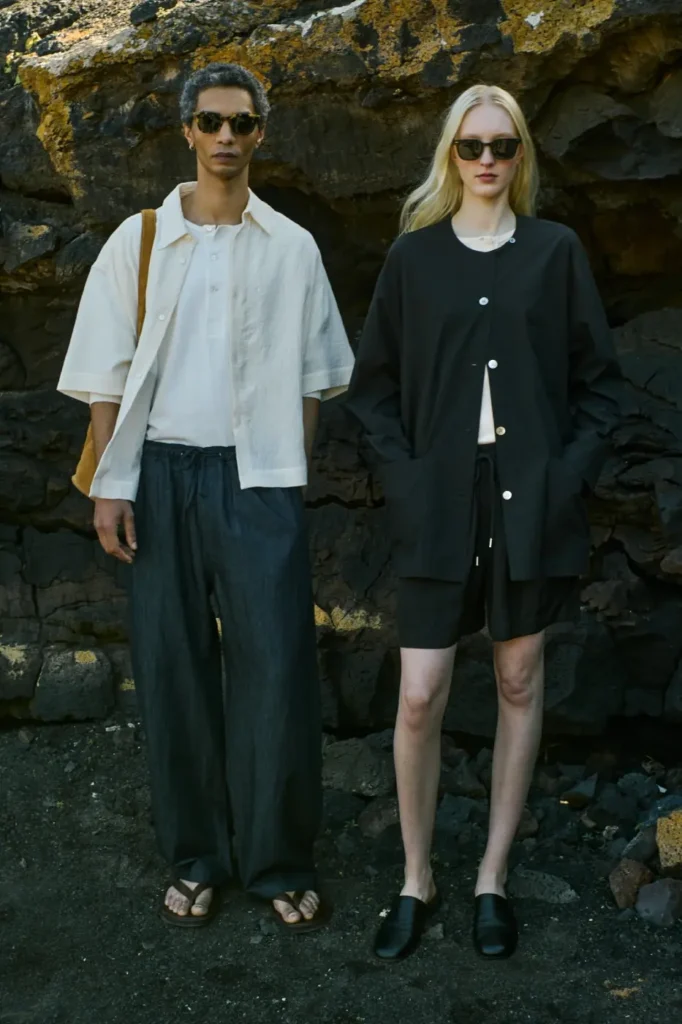 Studio Nicholson SS26 male and female models wearing relaxed gender neutral separates against a volcanic rock backdrop