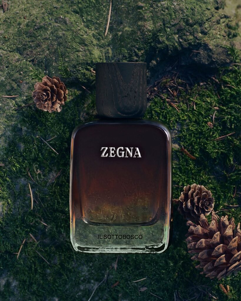 ZEGNA-MEMORIE-Il-Sottobosco-fragrance-bottle-in-deep-amber-brown-laid-on-a-mossy-forest-floor-surrounded-by-pine-cones-in-an-Oasi-Zegna-inspired-nature-setting