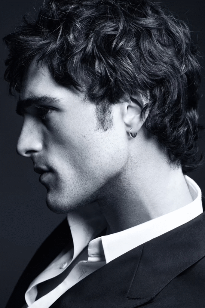 Jacob-Elordi-black-and-white-profile-portrait-for-Bleu-De-Chanel-2026-campaign-curly-hair-hoop-earring-dark-suit