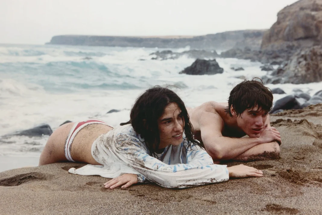 Nude Project 'Airplane Mode' collection campaign shot on film, two models on rocky shoreline.