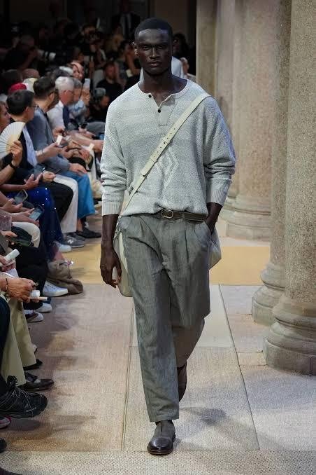 A-model-walks-the-Giorgio-Armani-SS27-menswear-runway-in-a-grey-knit-henley-and-trousers-with-a-crossbody-bag