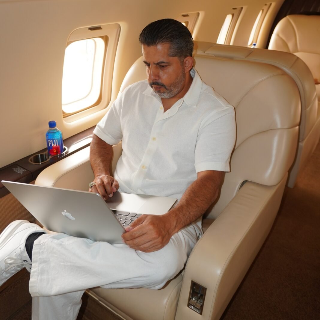 Dr. Paul Sran steps down the stairs of a private jet, dressed in an elegant all-white outfit, standing confidently on the aircraft steps under a dramatic cloudy sky at an airport runway