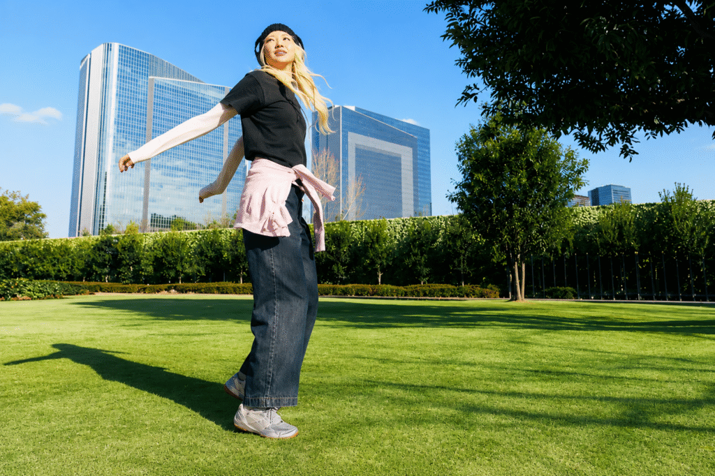 ASICS-Sensory-Bloom-Collection-editorial-illustration-of-a-woman-in-grey-lifestyle-sneakers-striding-across-a-sunlit-urban-park