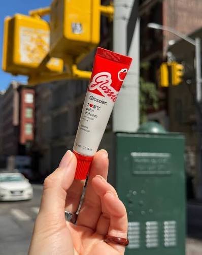 Hand-holding-a-Glossier-I-Love-NY-Balm-Dotcom-tube-on-a-New-York-City-street-corner_-with-yellow