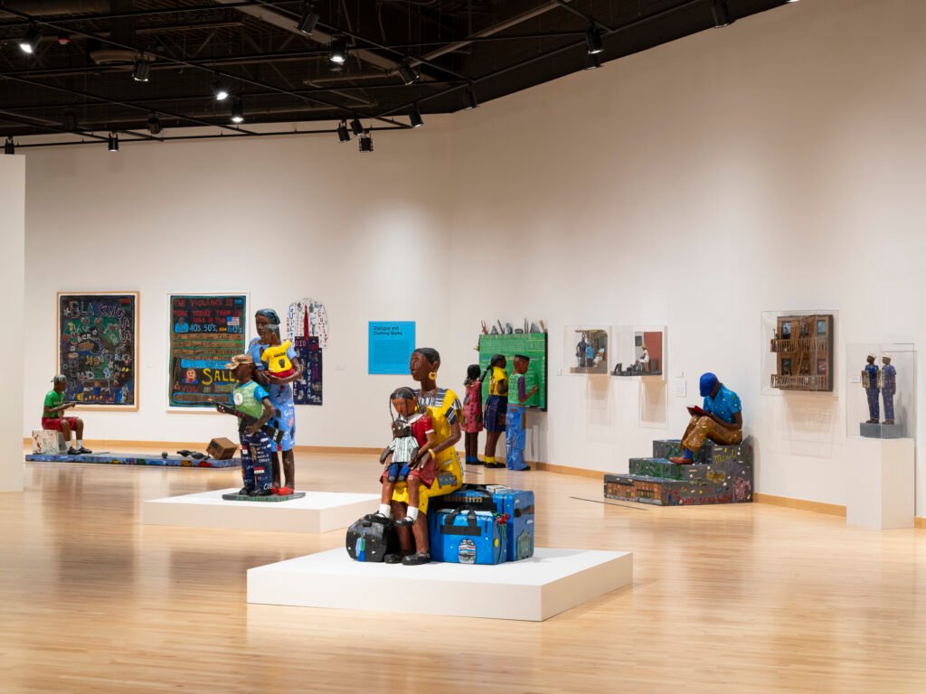 Installation view of Willie Birch Stories to Tell at CAAM, with painted papier-mâché figures and mixed-media works