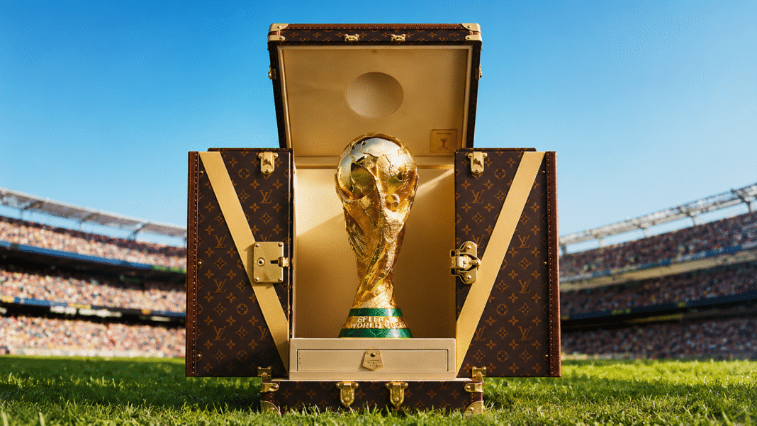 Louis-Vuitton-FIFA-World-Cup-2026-Trophy-Trunk-holding-the-gold-trophy-on-a-stadium-pitch