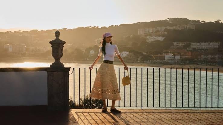 Model-in-Louis-Vuitton-crochet-knit-long-skirt-and-white-top-at-sunset-on-a-terrace-overlooking-the-coast