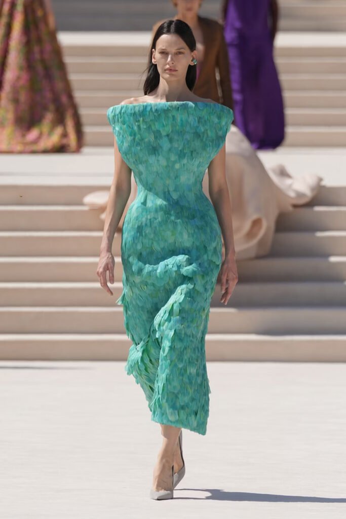 Model-in-a-fitted-turquoise-feather-textured-off-shoulder-midi-dress-and-taupe-pumps-on-the-Balenciaga-55th-couture-runway-in-Paris