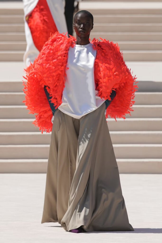 Model-in-a-scarlet-feathered-cropped-jacket-over-a-white-satin-top-and-wide-taupe-trousers-on-the-Balenciaga-55th-couture-runway-in-Paris