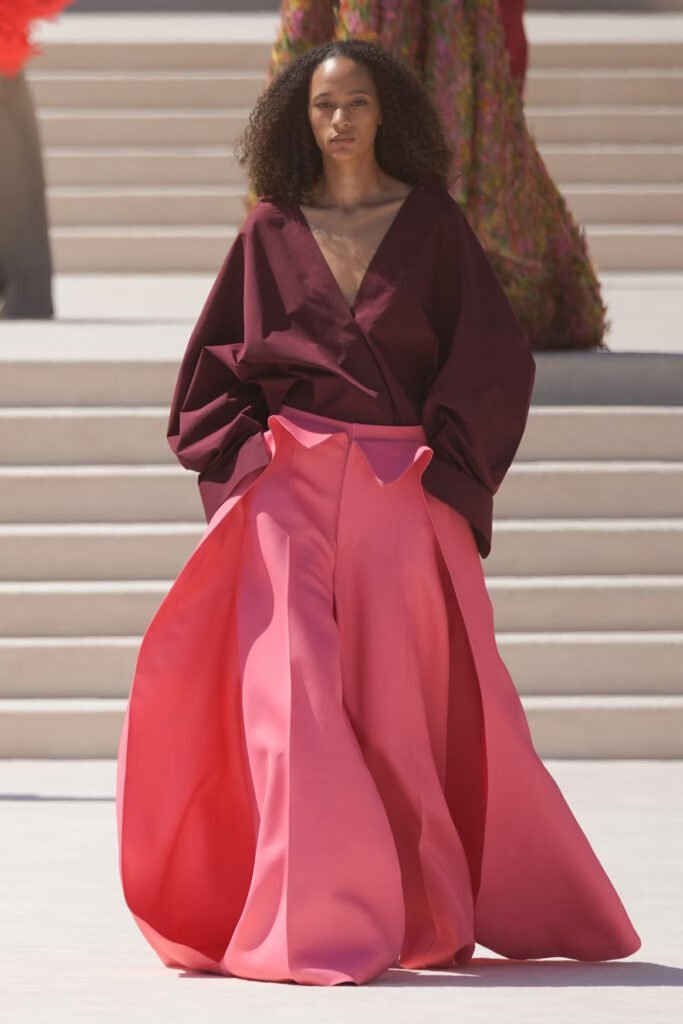 Model-in-an-oversized-burgundy-wrap-top-and-sculptural-wide-leg-pink-trousers-on-the-Balenciaga-55th-couture-runway-in-Paris