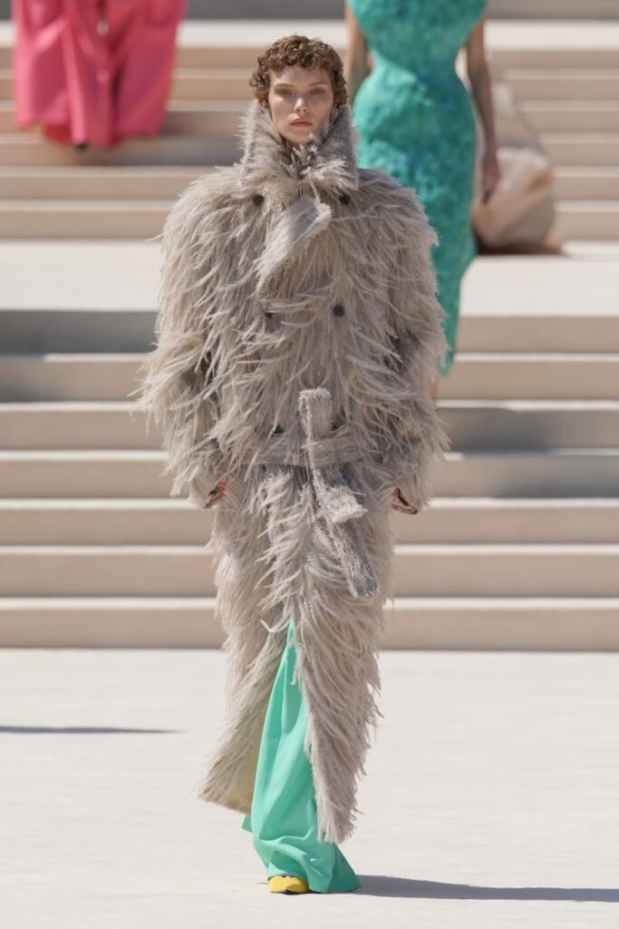 Model-in-an-oversized-grey-ostrich-feather-coat-over-mint-green-trousers-and-yellow-shoes-on-the-Balenciaga-55th-couture-runway-in-Paris