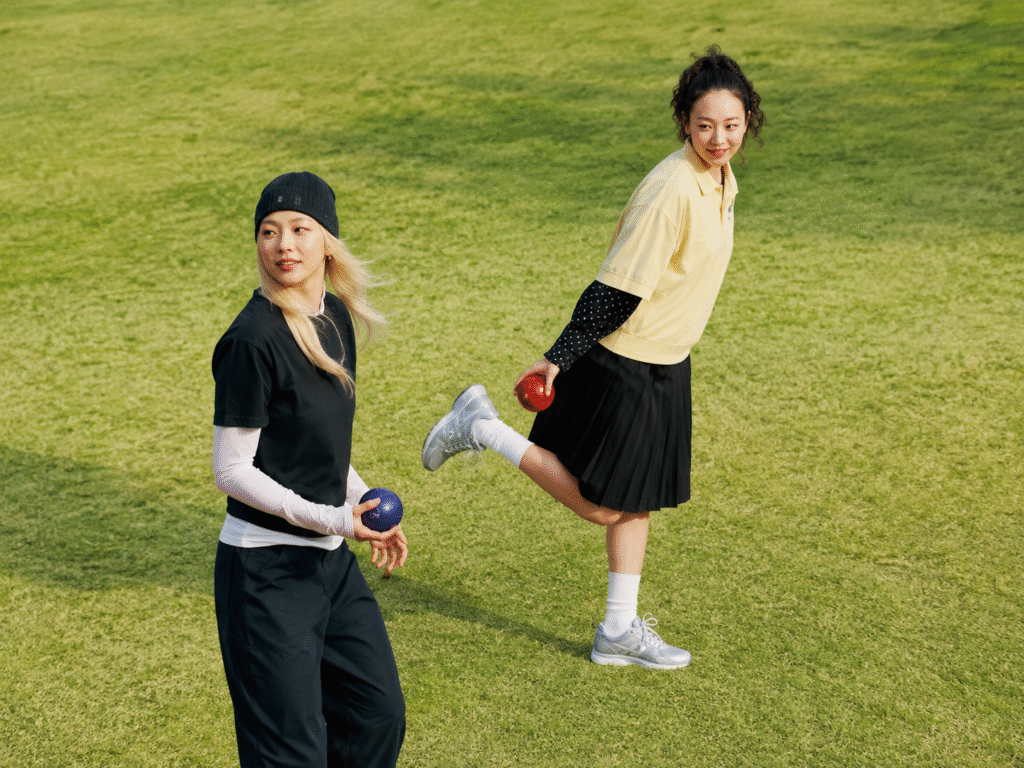 Two-women-play-lawn-bowls-in-sporty-streetwear-one-in-silver-sneakers-white-socks-and-a-black-pleated-skirt