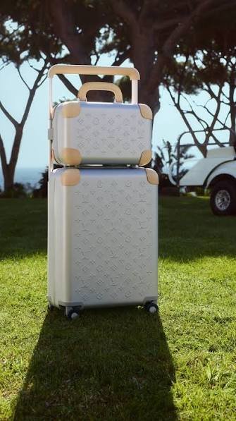 White-Louis-Vuitton-Monogram-embossed-rolling-luggage-set-with-leather-trim-on-a-seaside-lawn