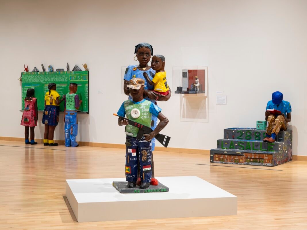 Willie-Birch-papier-mache-sculpture-of-a-mother-baby-and-boy-holding-a-toy-gun-on-view-at-CAAM-in-Los-Angeles