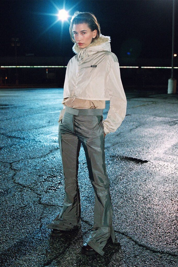 Hailey-Bieber-in-a-cream-cropped-hooded-jacket-and-grey-satin-flared-trousers-photographed-at-night-for-the-Miu-Miu-FallWinter-2026-campaign