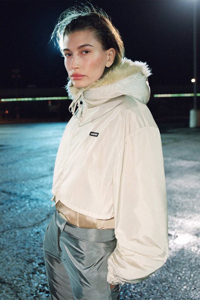 Hailey-Bieber-in-a-cream-fur-lined-hooded-jacket-and-grey-satin-trousers-photographed-at-night-for-the-Miu-Miu-FallWinter-2026-campaign