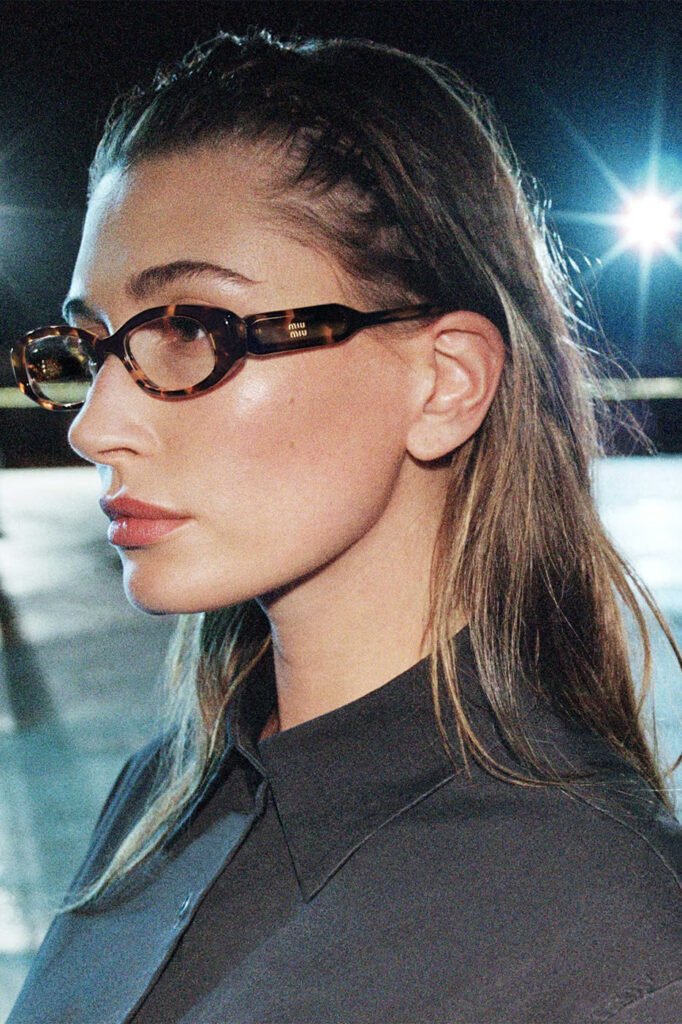 Hailey-Bieber-in-profile-wearing-tortoiseshell-Miu-Miu-glasses-and-a-grey-shirt-photographed-at-night-for-the-Miu-Miu-FallWinter-2026-campaign
