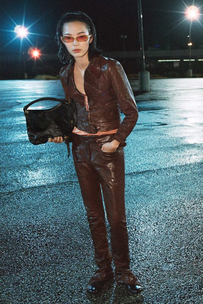 Xiao-Wen-Ju-in-a-brown-leather-jacket-and-matching-trousers-holding-a-black-Miu-Miu-shoulder-bag-photographed-at-night-for-the-Miu-Miu-FallWinter-2026-campaign