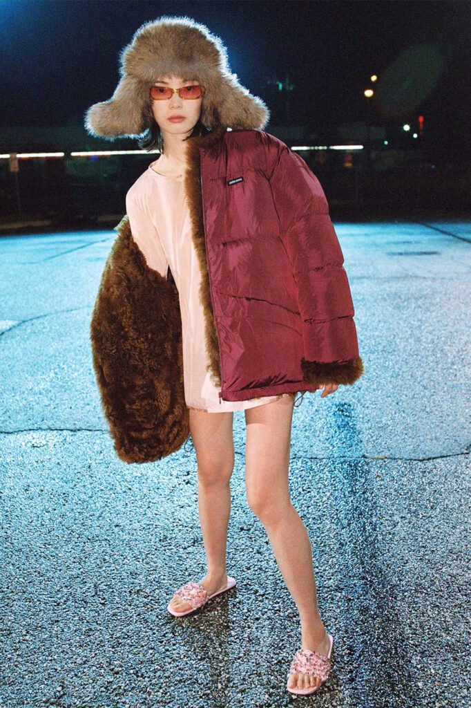 Xiao-Wen-Ju-in-a-fur-trapper-hat-burgundy-fur-trimmed-puffer-jacket-over-a-pink-slip-dress-and-embellished-slides-photographed-at-night-for-the-Miu-Miu-FallWinter-2026-campaign