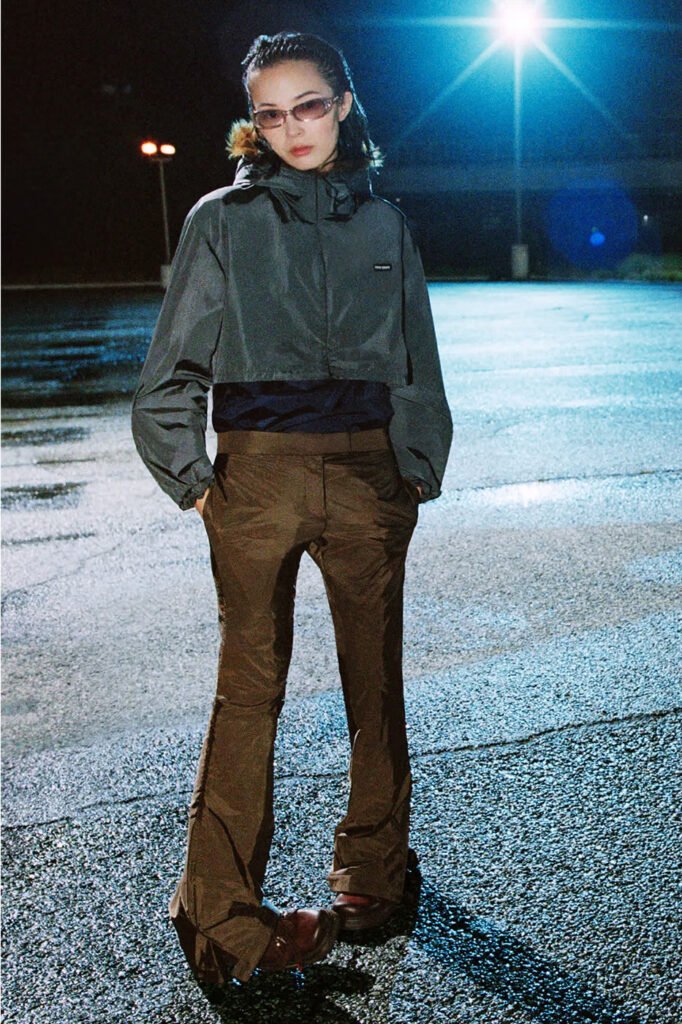 Xiao-Wen-Ju-in-a-grey-cropped-hooded-jacket-and-brown-satin-flared-trousers-photographed-at-night-for-the-Miu-Miu-FallWinter-2026-campaign