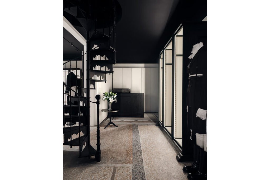 Ann-Demeulemeester-Palais-Royal-store-in-Paris-with-a-black-spiral-staircase-white-lilies-and-lit-cabinets-on-a-mosaic-floor