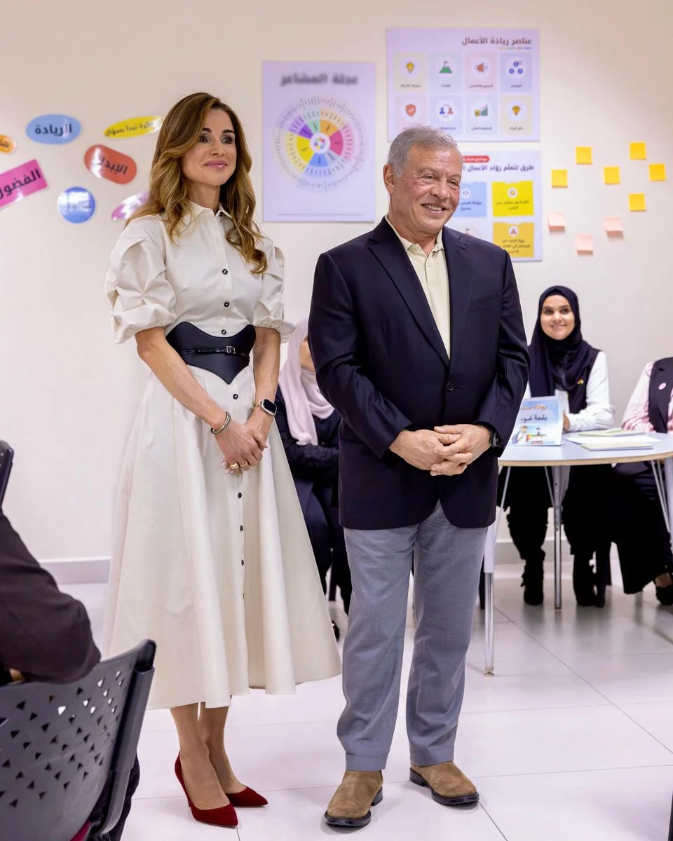 Queen-Rania-in-an-ivory-puff-sleeve-shirtdress-with-a-black-corset-belt-beside-King-Abdullah-II-at-a